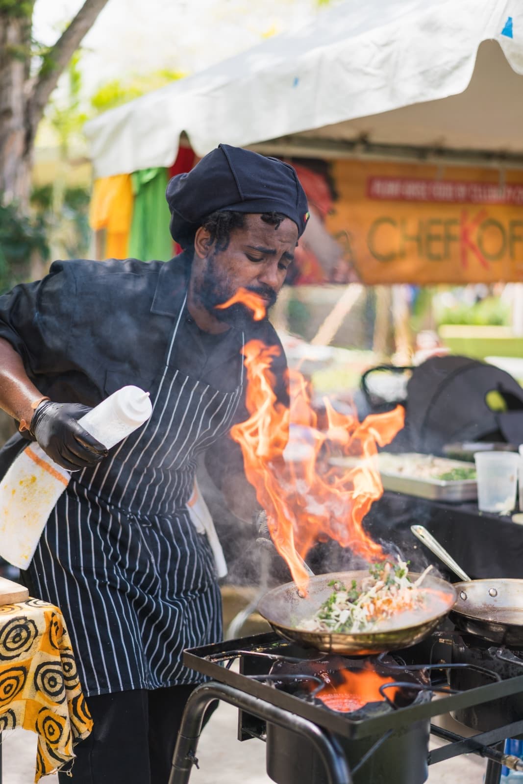 Flambéing a wok over open flame at a live event, The Dine369 Experience